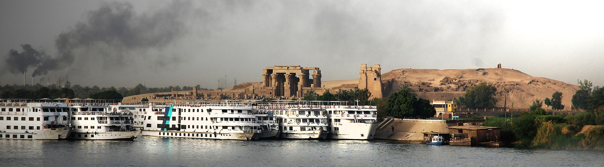 Cruise ships moored below a riverside temple ruin